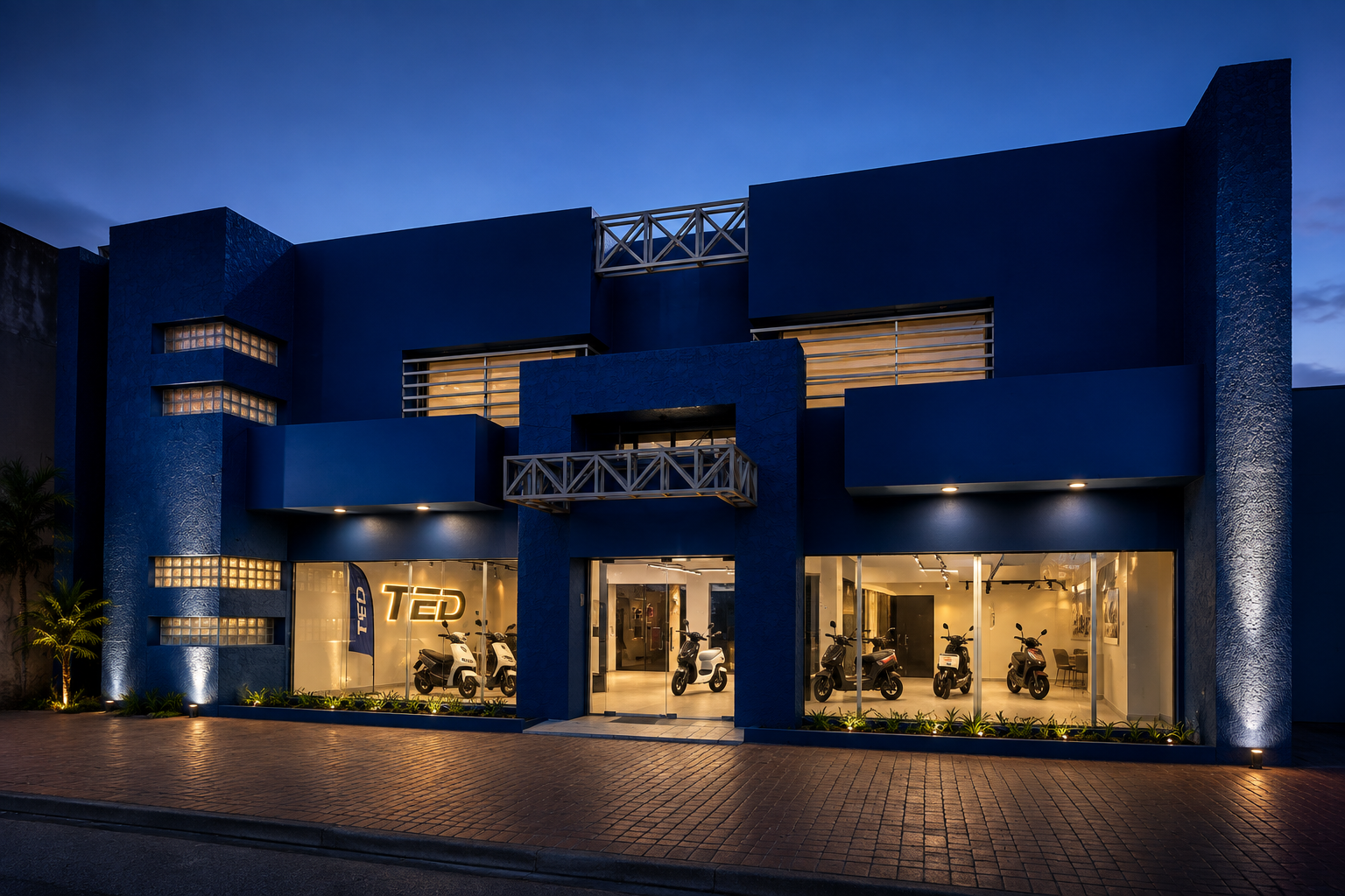 Fachada del showroom TED en Santa Cruz al anochecer, con las motocicletas visibles a través del vidrio